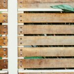 Close-up of a rustic wooden fence with green leaves peeking through the gaps.
